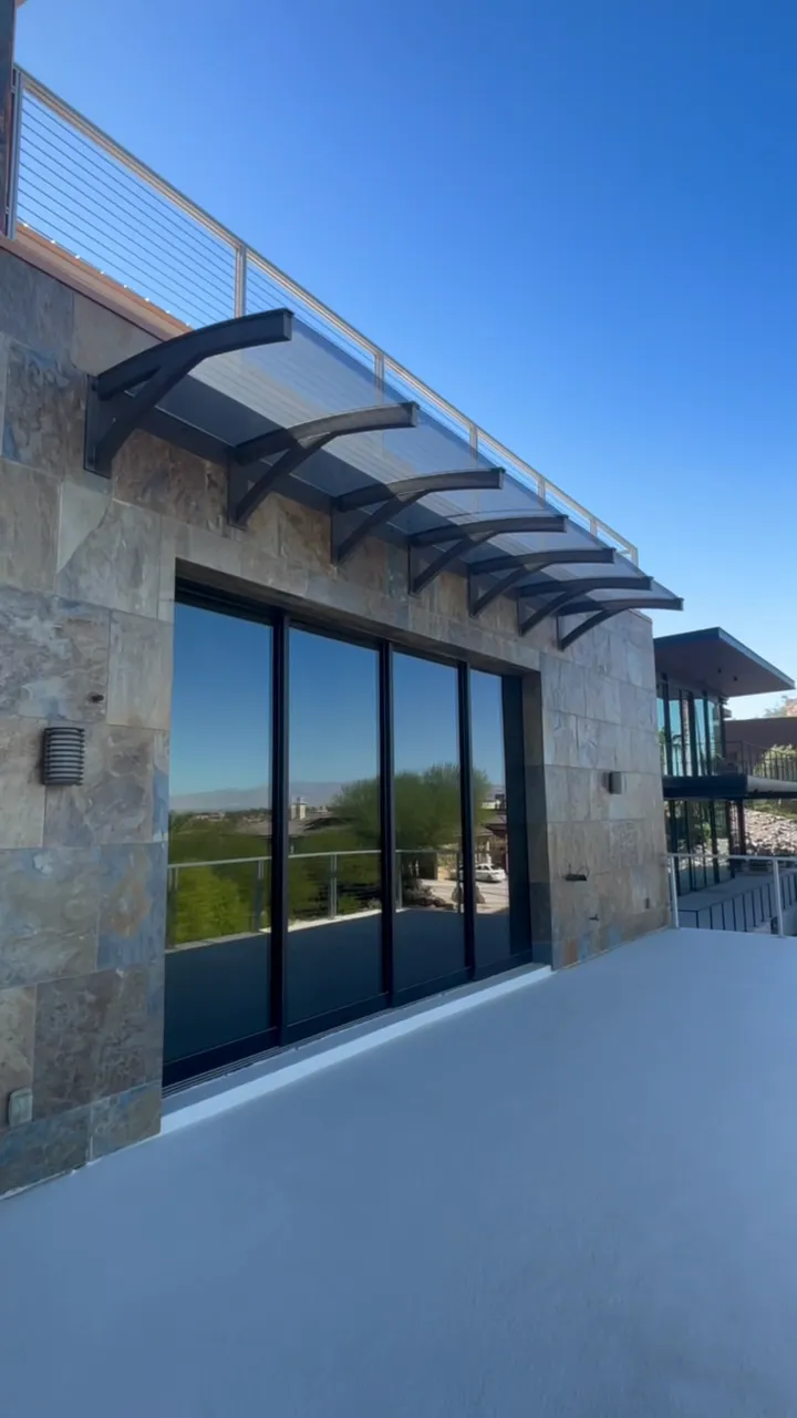Balcony with a wall of sliding glass doors under a steel awning