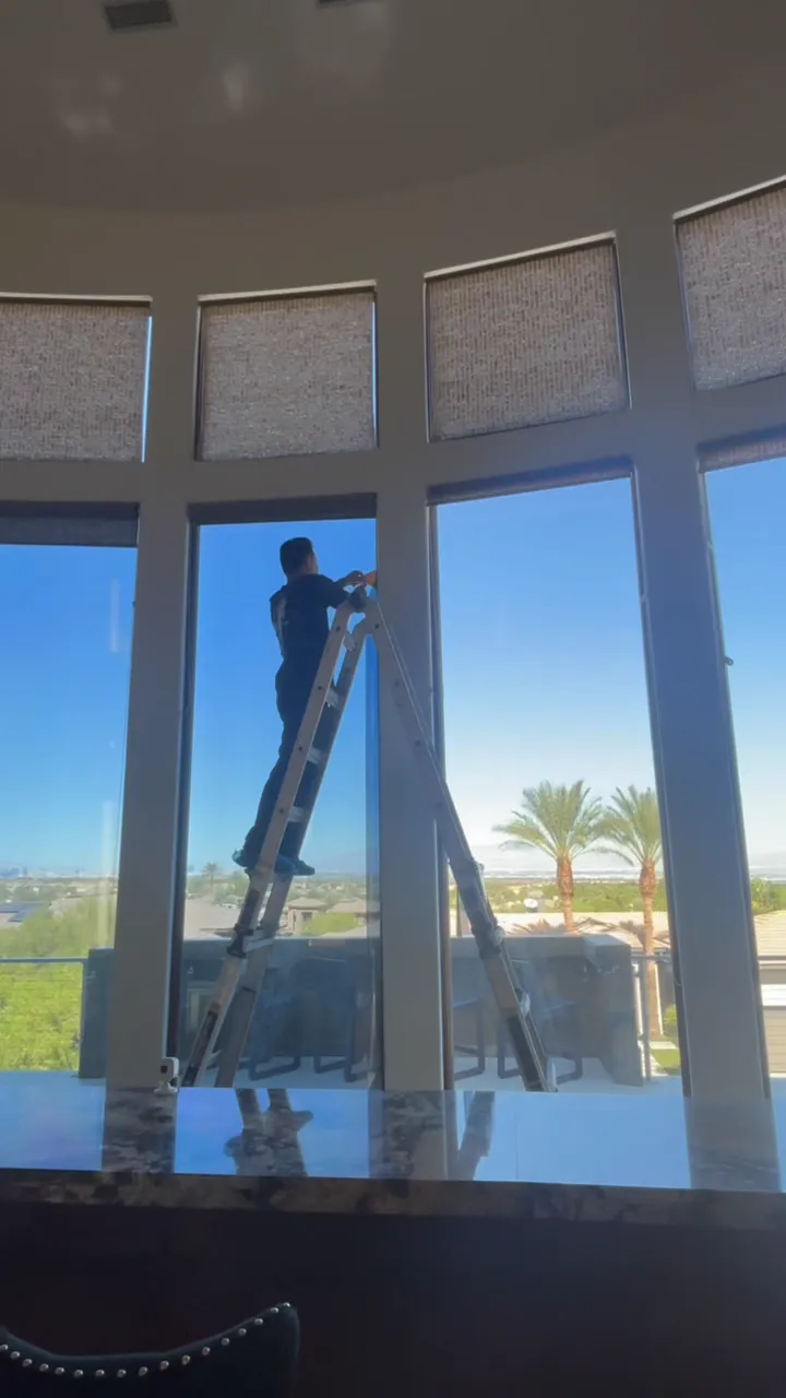 Installer on a ladder fitting film to a tall curved window